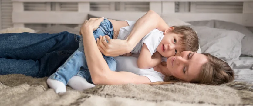 Mother and child lying together on a bed in a calm affectionate moment