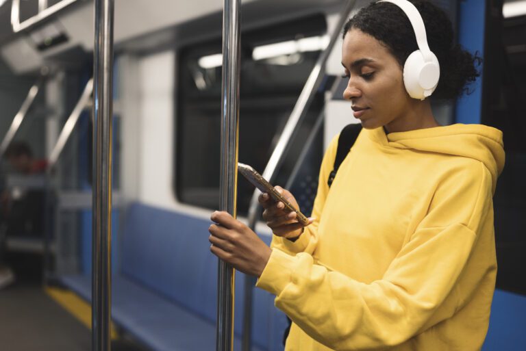 Woman wearing headphones on a subway train, using the Begin Mindfulness app offline