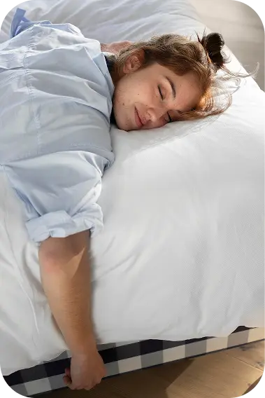 Young woman peacefully sleeping face-down on a white bed, illustrating a mindful bedtime routine
